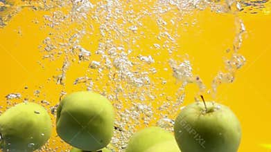 Green apples falling into water