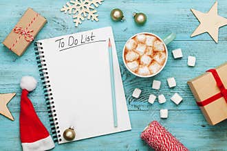 Cup of hot cocoa or chocolate with marshmallow, holiday decorations and notebook with to do list, christmas planning. Flat lay.