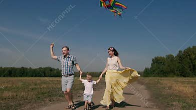 Joyful family flying a kite and running on the road with it