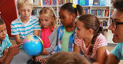 Kids and teacher looking at globe in library