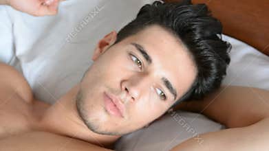 Shirtless male model lying alone on his bed