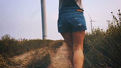 Happy girl running towards the wind turbine, slow motion.