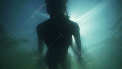 Underwater silhouette of girl diving in the sea