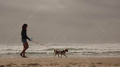 Young woman walking dog beach