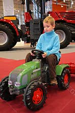 Boy astride small tractor