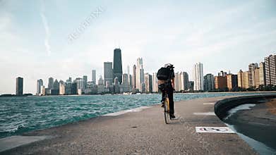 Cyclist rides at seaside with skyscrapers on the background