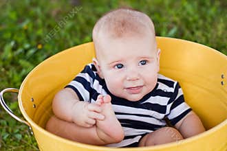 White 7-month-old baby in yellow bucket