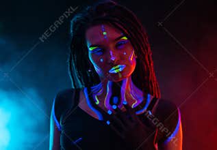 Cocky Girl with Dreadlocks in Ultraviolet neon light with Foggy Background. Bodyart