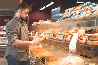 Portrait of a man who buys a bun at the supermarket`s bread department. Buyer chooses bread in a supermarket. Buying products at
