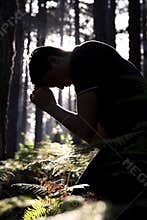 Man kneeling and praying in the forest
