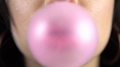 Girl with pink lipstick blowing bubble gum closeup in slow motion