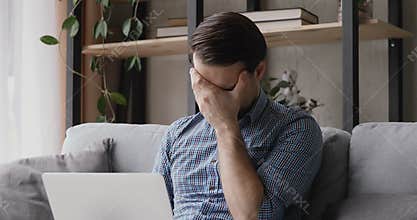 Man sitting with laptop received badly news feels frustrated annoyed