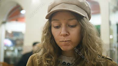 Woman in a newsboy cap eating traditional portuguese dessert pastel de nata and drinking coffee in cafe slow motion