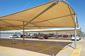 An outdoor car park with shade canopies in a shopping centre.