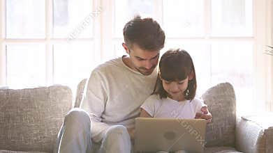 Caring father teaches little daughter how computer work