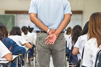 School exam room with teacher invigilator watching over students having stress studying in class or monitoring candidates