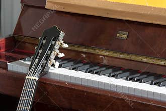 Classical music. Acoustic guitar resting on an old piano close-up