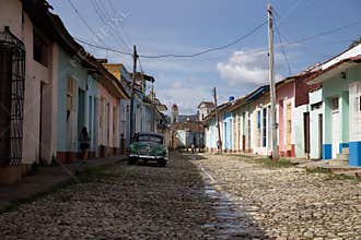 Trinidad, Cuba - October 10, 2017: Colorful streets and traditional houses of trinidad and a green old cuban car parked on a sunny