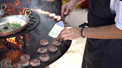 The chef grills meatballs for mini burgers on the grill.