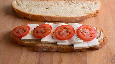 Serving a toast from homemade bread with tomato and fresh cheese. Pour olive oil on sandwich. Healthy vegetarian food
