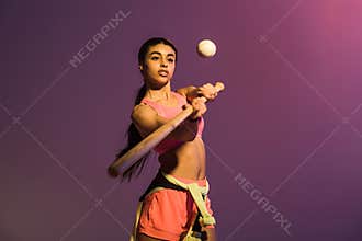 Sportive african american girl playing baseball on purple background