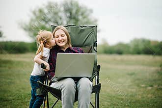 Chat online with family on laptop on picnic in nature. Homeschooling, freelance job. Mom and child. Mother work on Internet with
