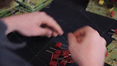 Hands inserting electronic component into printed circuit board - close up
