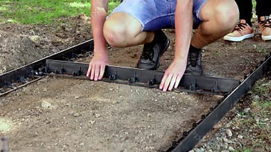 Young children constructing a path, laying delimiter panel