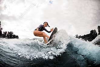 Young cheerful woman is engaged in wake surfing
