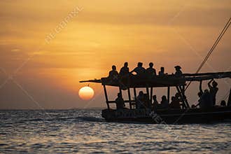 Dhow sailing during sunset in Zanzibar. Dhow is a wooden vessel with a sail, used to transport goods. Mostly used in
