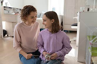 Happy mom and teen daughter play with domesticated mouse