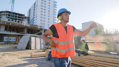Happy and charismatic Afro American guy construction worker dancing funny at the lunch time beside his colleagues from