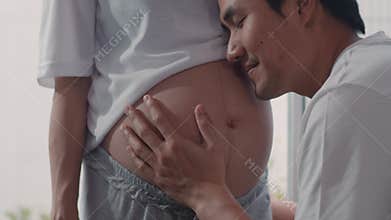 Young Asian Pregnant couple man kiss his wife belly talking with his child. Mom and Dad feeling happy smiling peaceful while take