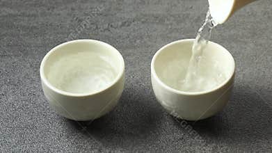 Pouring traditional Japanese sake in cups