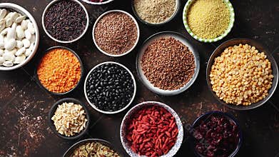 Various superfoods in smal bowls on dark rusty background