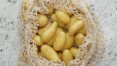 Young fresh Potatoes in a ecological zero-waste net bag placed on white scratched background