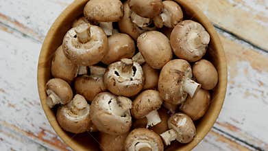 Fresh mushrooms in wooden bowl placed on white wooden table