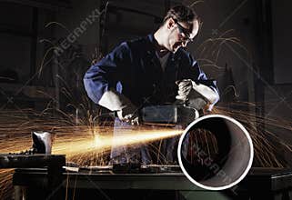 Worker cutting pipe with angle grinder.