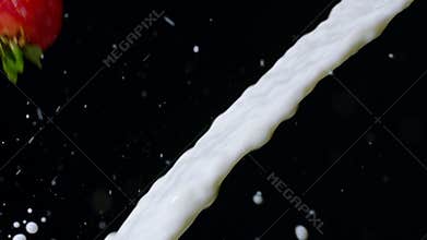 Strawberry fruits flying into stream of milk with beautiful spatter slow mo