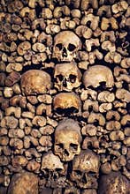 Stack of skulls and bones in the shape of a cross in the catacombs of Paris France
