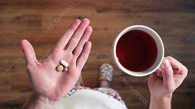 Sick man is taking pills and drinking hot tea