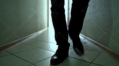 Man in shoes walks down a dirty corridor forward on camera, close-up