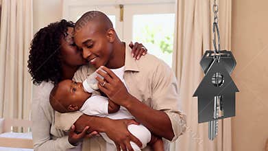 House keys and key fob hanging with couple with baby in new home in the background