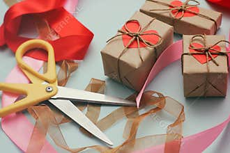 Process of packaging gift boxes. Thanks gifts. Wedding presents. Pink ribbon and yellow scissors. Red carton hearts.