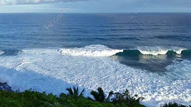 Crashing Surf Against A Palm Covered Cliff In Kauai, Hawaii