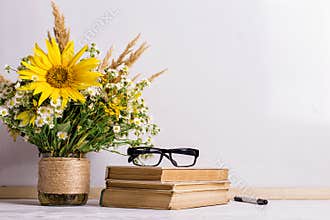 Books, glasses, markers and a bouquet of flowers in a vase on white board background. Concept for teachers day and first September