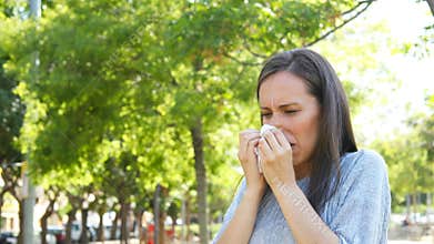 Woman sneezing outdoor in a park