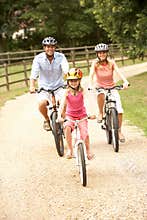 Family Cycling In Countryside Wearing Safety Helme