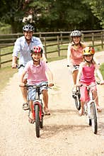 Family Cycling In Countryside Wearing Safety Helme