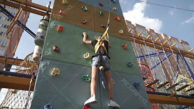 Active young girl on adventure park, training climbing. Child to pass difficult section of an obstacle course. Active